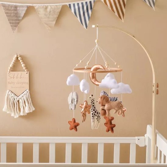 Mobile bebe décorative pour lit de bébé avec animaux de la jungle et fanions muraux, créant une ambiance douce et naturelle.