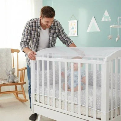 Father gently placing baby in white crib with cozy bedding and nursery decor