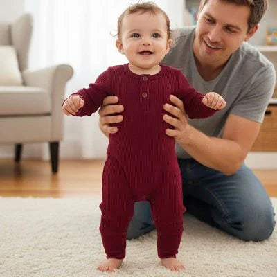 Baby in cozy maroon onesie, supported by dad, perfect for sweet sleep and comfort