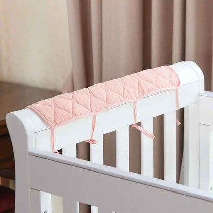 Soft pink quilted crib rail cover for baby’s safe and cozy sleep