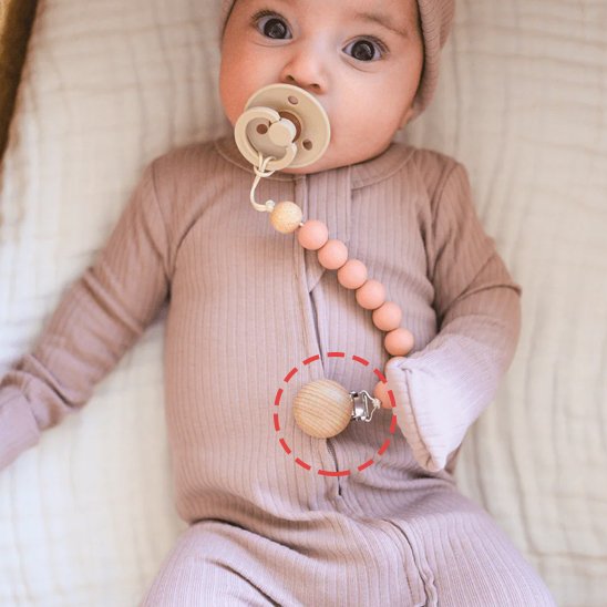Baby wearing soft ribbed onesie with wooden pacifier clip and beads for cozy sleep