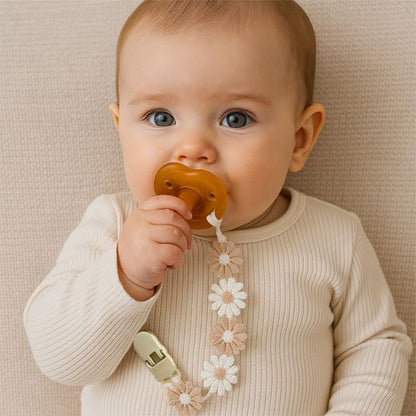 Baby with floral pacifier clip and amber soother, cozy sleep accessory for gentle nights