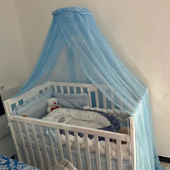 Blue canopy over white baby crib with plush toy and soft bedding for cozy infant sleep