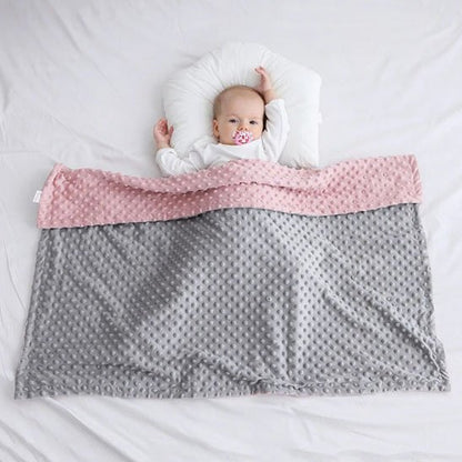 Baby sleeping peacefully under soft pink and gray minky blanket, ideal for gentle bedtime comfort.