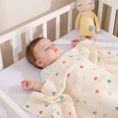 Baby sleeping peacefully in crib under colorful heart-patterned blanket, cozy nursery setting
