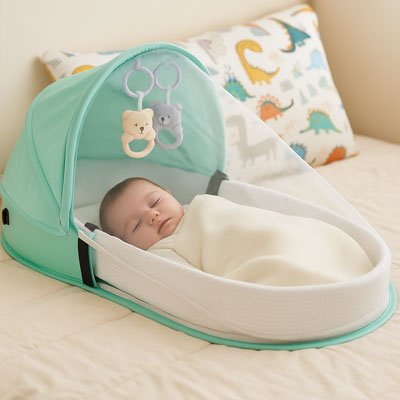 Bébé endormi dans un lit bébé portable avec moustiquaire et jouets suspendus, idéal pour un sommeil doux et sécurisé.