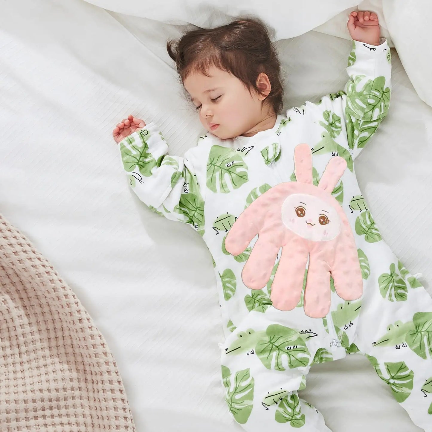 Baby sleeping in leaf-print onesie with pink bunny appliqué, cozy bedtime comfort for sweet dreams