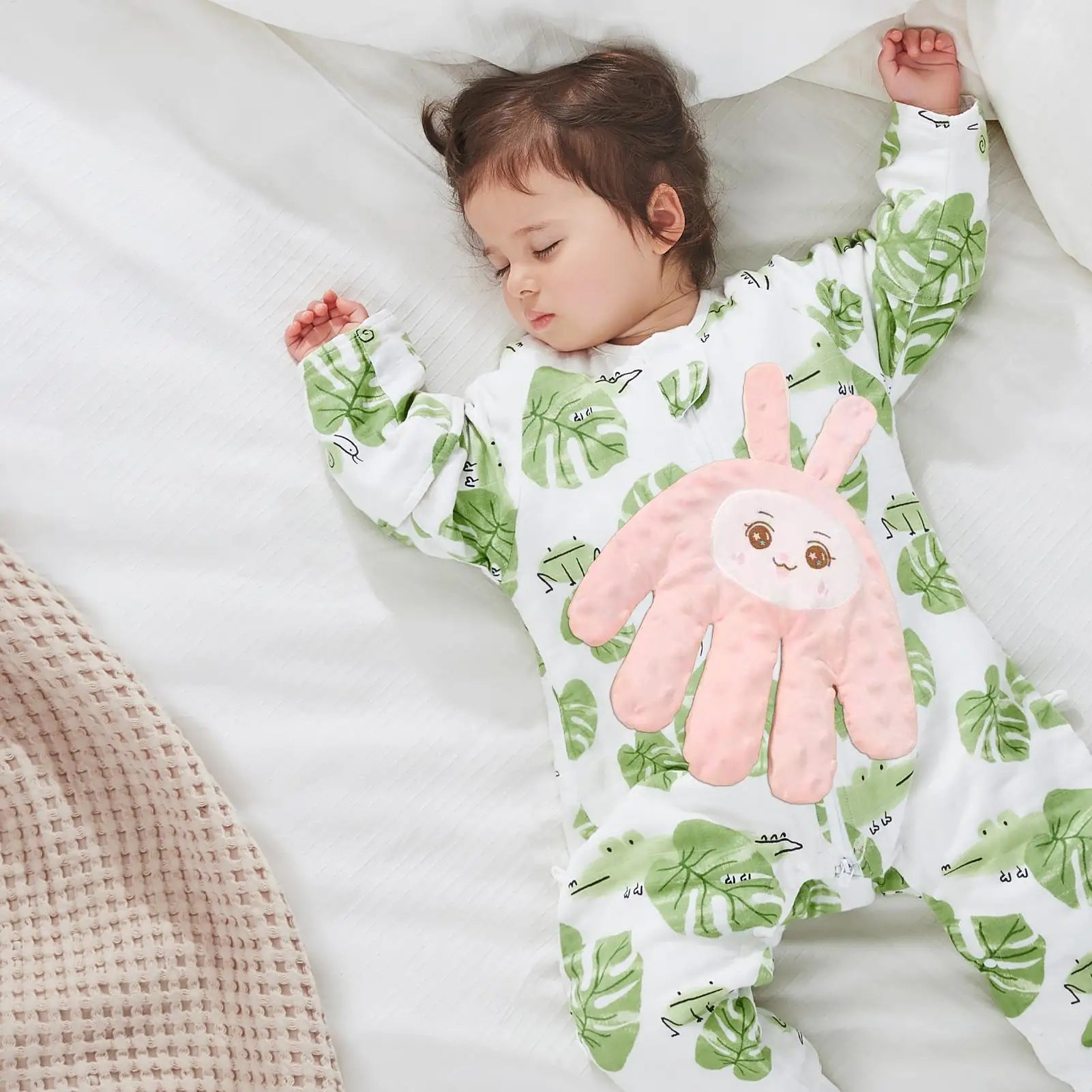 Baby sleeping in leaf-print onesie with pink bunny appliqué, cozy bedtime comfort for sweet dreams