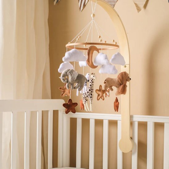 Mobile de lit bébé en bois avec figurines en feutrine d'éléphant et de girafe, nuages blancs et étoiles suspendus au-dessus d'un berceau