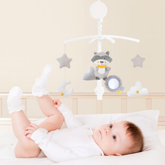 Mobile musical motorisé pour berceau avec une peluche douce de raton laveur gris, un miroir d'éveil et des étoiles suspendus au-dessus d'un bébé couché.