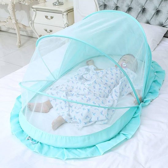 Baby sleeping peacefully under mint green mosquito net on bed, cozy nursery setting