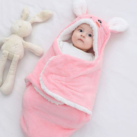 Baby wrapped in pink bunny hooded swaddle blanket with plush toy, cozy sleep essentials