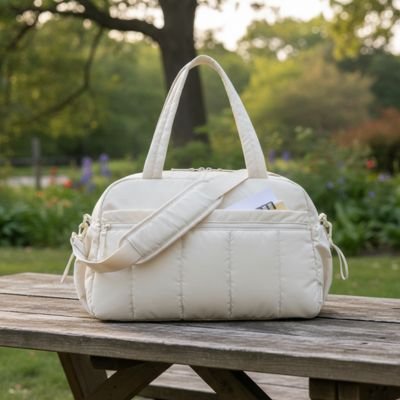 Cream quilted diaper bag on wooden bench in garden, perfect for baby essentials and outings