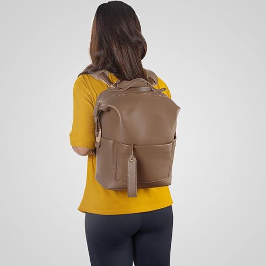 Brown leather diaper bag backpack with front pocket, worn by woman in yellow shirt