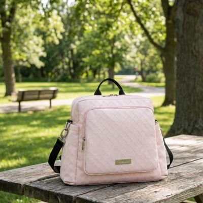 Pink quilted diaper bag on wooden picnic table in sunny park, perfect for baby essentials and outings