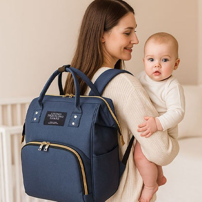 Navy blue diaper bag with gold zippers, worn by mom holding baby, ideal for baby essentials and travel
