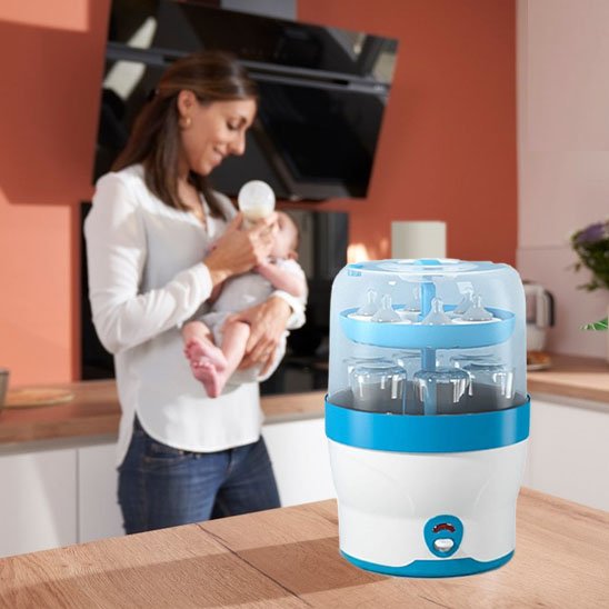 Baby bottle sterilizer and dryer with mom feeding baby in kitchen, safe infant care essentials
