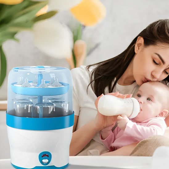Mother feeding baby with bottle beside baby bottle sterilizer for safe feeding