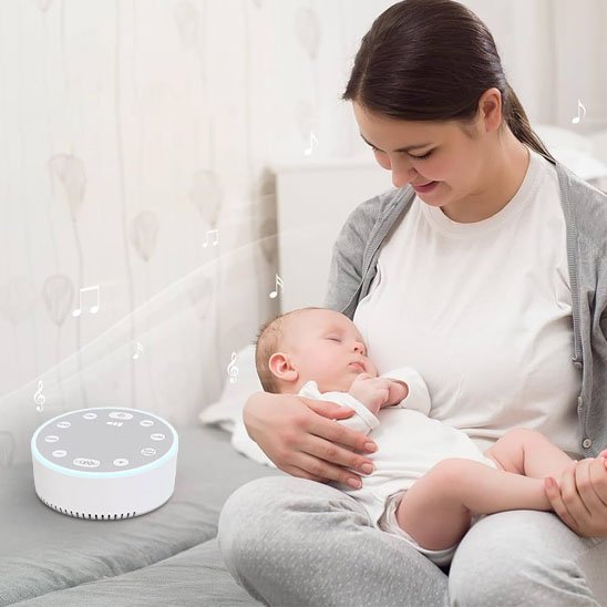 Mother holding sleeping baby with white noise machine for peaceful baby sleep